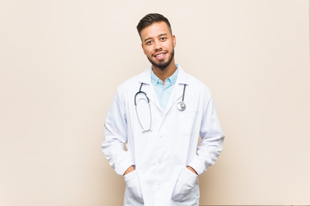 Homem jovem médico sul-asiático feliz, sorridente e alegre.