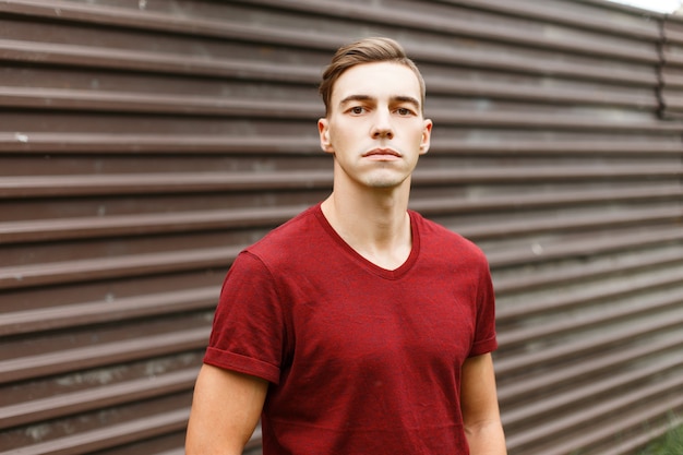 Homem jovem moderno elegante com um corpo desportivo com um penteado elegante em uma camiseta vermelha elegante.