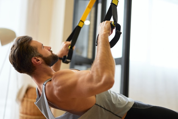 Homem jovem musculoso fazendo exercícios com faixa elástica de fitness