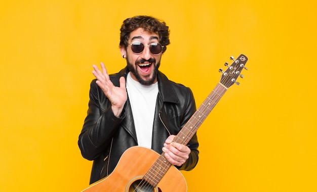 Homem jovem músico se sentindo chocado e animado, rindo, espantado e feliz por causa de uma surpresa inesperada com um conceito de guitarra, rock and roll