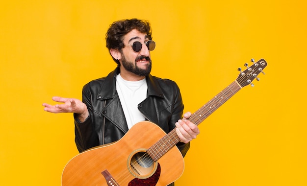 Homem jovem músico se sentindo sem noção e confuso, não tenho certeza qual escolha ou opção para escolher, pensando com um conceito de guitarra, rock and roll