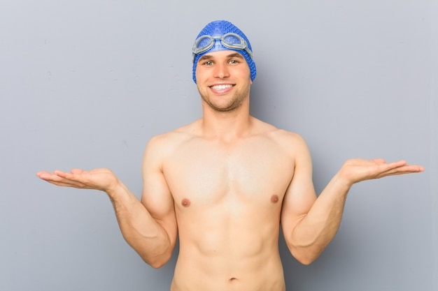 Homem jovem nadador profissional faz escala com os braços, sente-se feliz e confiante.
