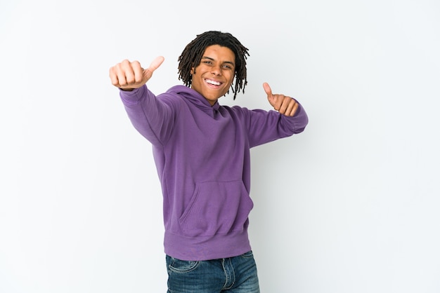 Homem jovem rasta americano africano levantando os dois polegares, sorrindo e confiante.