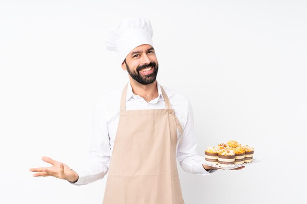 Homem jovem, segurando, bolo muffin, sobre, isolado, branca, sorrindo