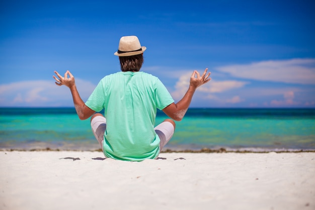 Homem jovem, sentando, em, posição lotus, ligado, praia branca areia