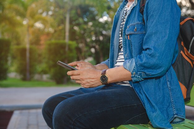 Homem jovem, sentando, telefone, em, parque público, em, outono