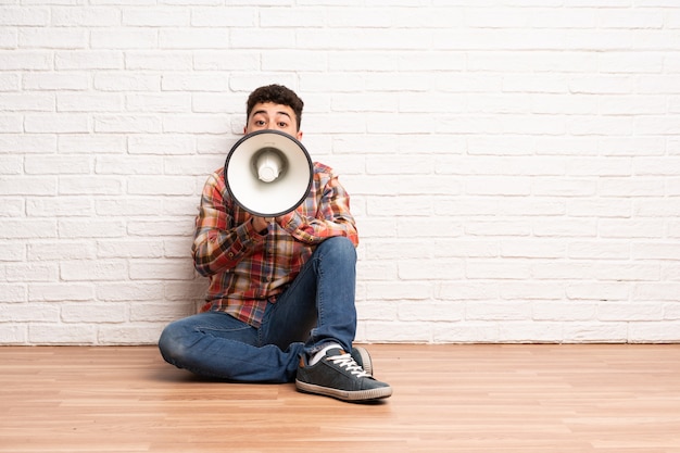 Homem jovem, sentar chão, shouting, através, um, megafone