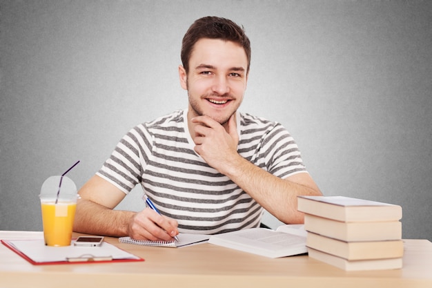 Homem jovem, sentar-se à mesa, com, um, pilha livros