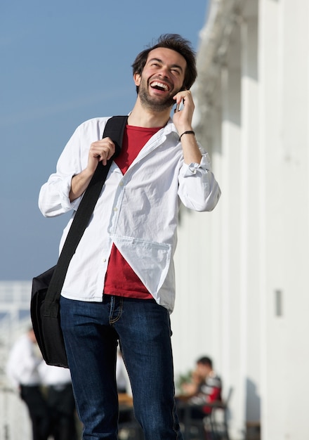 Homem jovem, sorrindo, ao ar livre, com, telefone móvel