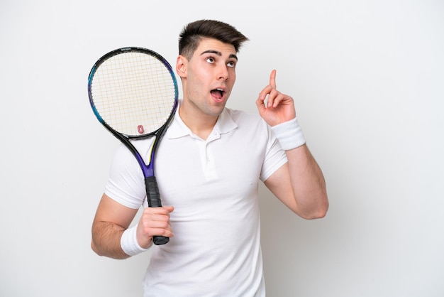 Homem jovem tenista isolado no fundo branco pensando em uma ideia apontando o dedo para cima