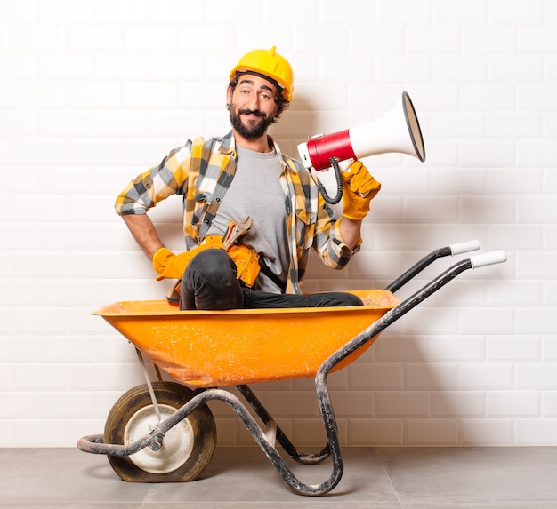 Foto homem jovem trabalhador da construção civil barbudo em um carrinho de mão