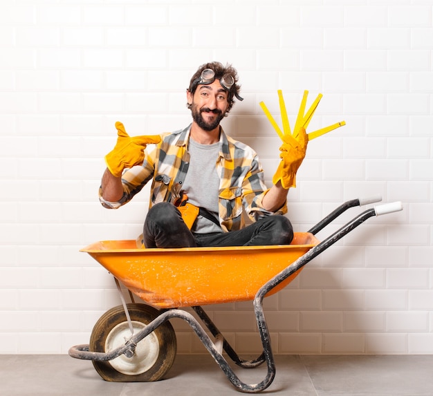 Foto homem jovem trabalhador da construção civil barbudo em um carrinho de mão