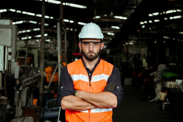 Homem jovem trabalhador industrial trabalhando com máquina de metal em fábrica com muitos equipamentos