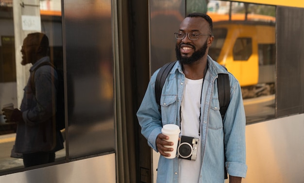 Homem jovem turista adulto com café na estação de trem