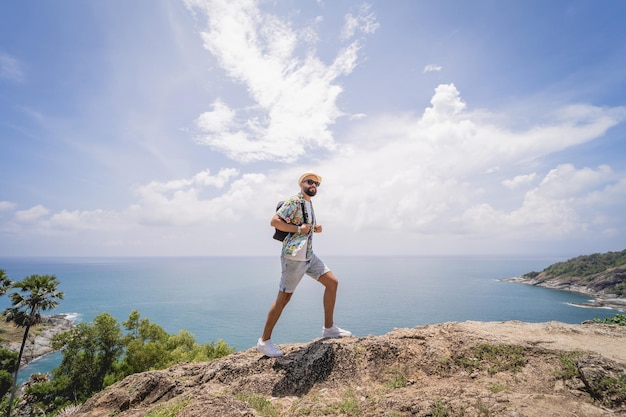 Homem jovem viajante nas férias de verão com belas montanhas e paisagens marítimas ao fundo