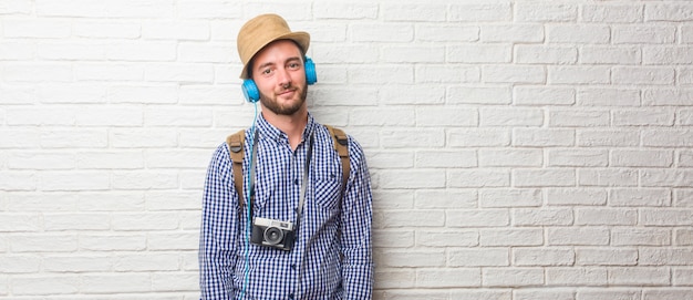 Homem jovem viajante usando mochila e uma câmera vintage alegre e com um grande sorriso, co