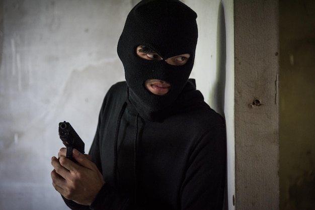 Homem ladrão ladrão usa máscara segurando arma escondendo armado esperando criminoso