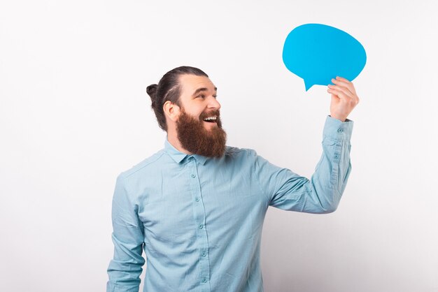 Homem largo e sorridente está olhando para o discurso de bolha azul que ele está segurando.