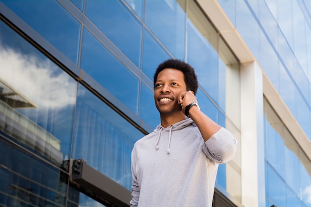 Homem latin novo que fala no telefone móvel fora.