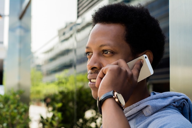 Homem latin novo que fala no telefone móvel fora.