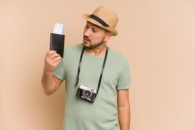 Foto homem latino adulto segurando bilhetes de avião para viajar isolado