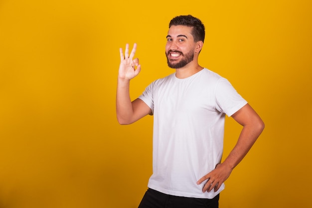 Homem latino-americano brasileiro com gesto ok fazendo ok com os dedos alegre feliz sorrindo otimista