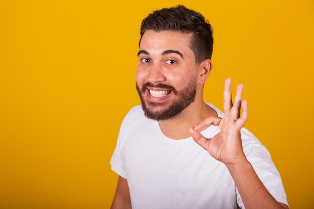 Homem latino-americano brasileiro com gesto ok fazendo ok com os dedos alegre feliz sorrindo otimista