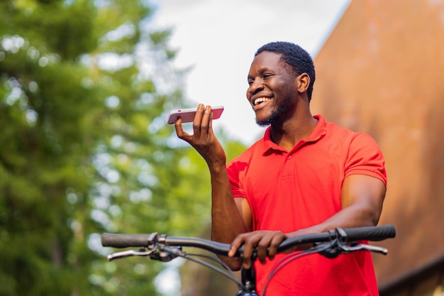 Homem latino-americano em roupas casuais sorrindo enquanto se apoia em sua bicicleta