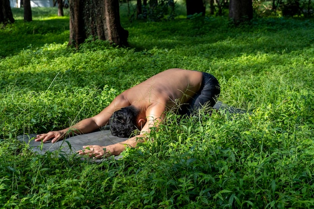 Homem latino-americano fazendo postura de ioga postura de ioga Abelha para trás Prsthatah Brahmara floresta