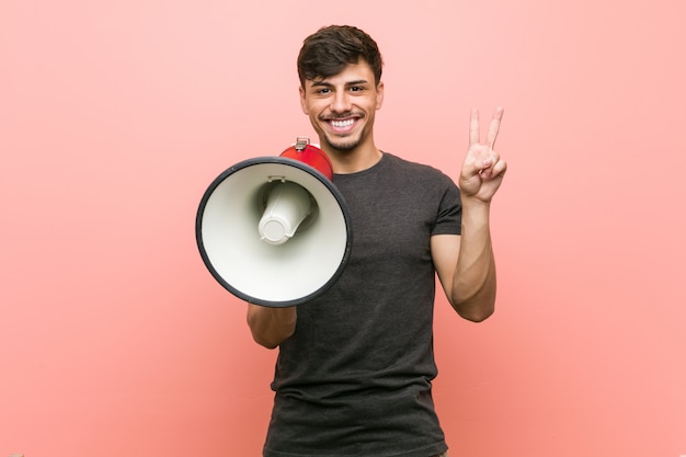 Homem latino-americano novo que guarda um megafone que mostra o número dois com dedos.