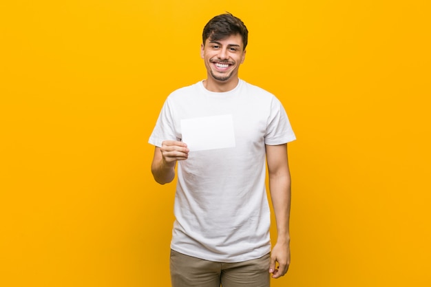 Homem latino-americano novo que mantém um cartaz feliz, sorridente e alegre.