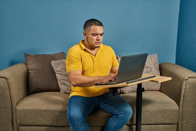 Homem latino-americano trabalhando em casa e se preparando em seu computador