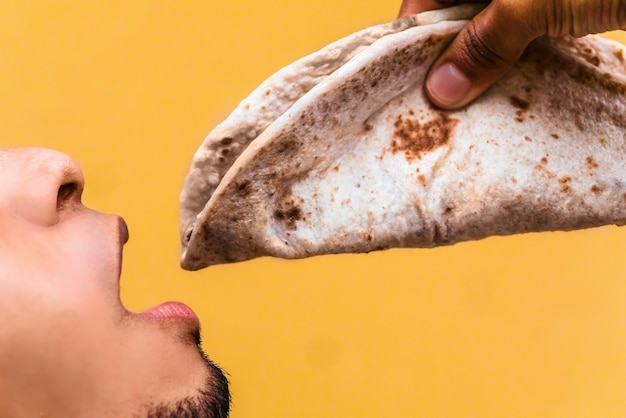 Homem latino com a boca aberta para comer comida típica hondurenha chamada baleada