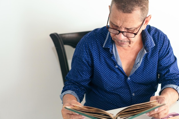 Homem latino com álbum de fotos na sala de sua casa