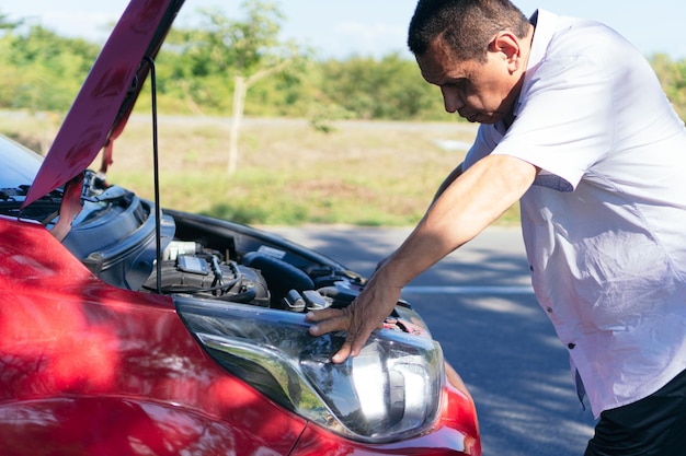 Foto homem latino consertando seu carro na estrada.