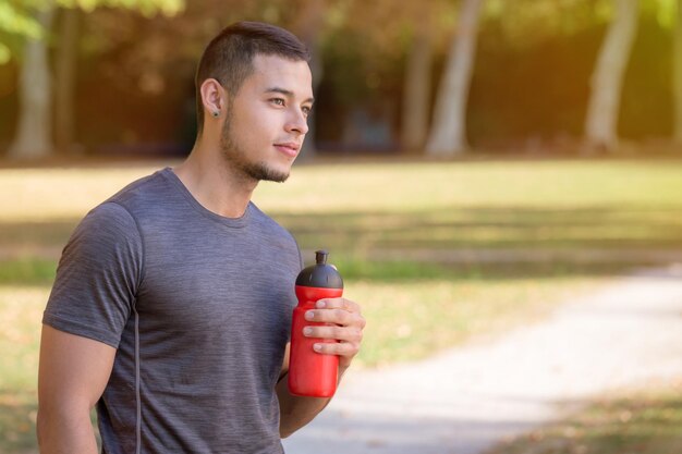 Homem latino corredor olhando pensando garrafa de água correndo corrida esportes treinamento fitness copyspace