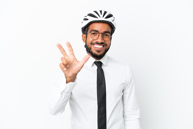 Homem latino de negócios jovem segurando um capacete de bicicleta isolado no fundo branco feliz e contando três com os dedos