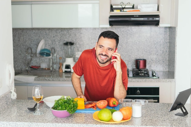 Homem latino falando no celular enquanto prepara o café da manhã em casa