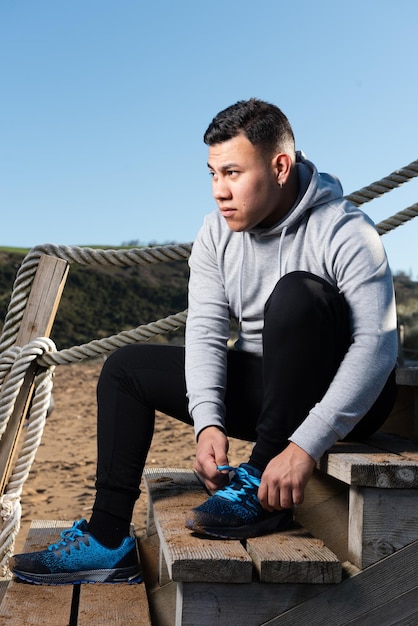 Homem latino focado amarrando sapatos esportivos antes do treino.