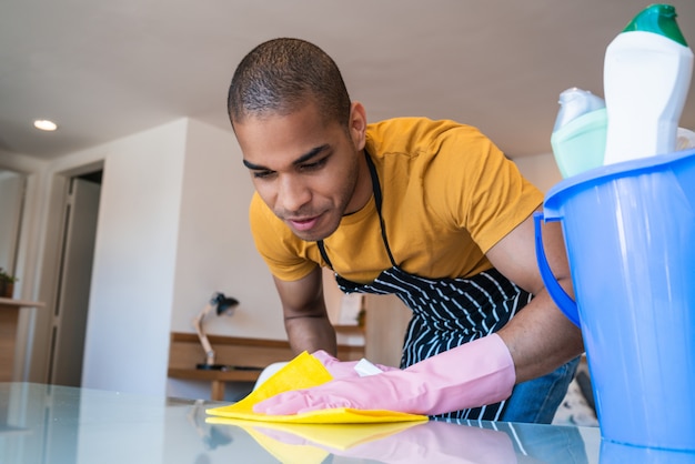 Homem latino novo que limpa em casa.