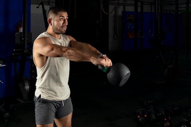 Homem latino se exercitando com um kettlebell em uma academia