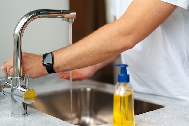 Homem lavando as mãos com sabão em uma pia em sua casa