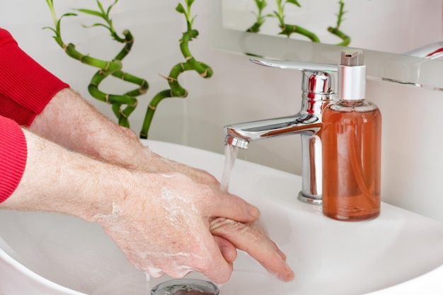 Homem lavando as mãos com sabão na pia do banheiro moderno prevenção de vírus lavando as mãos com frequência