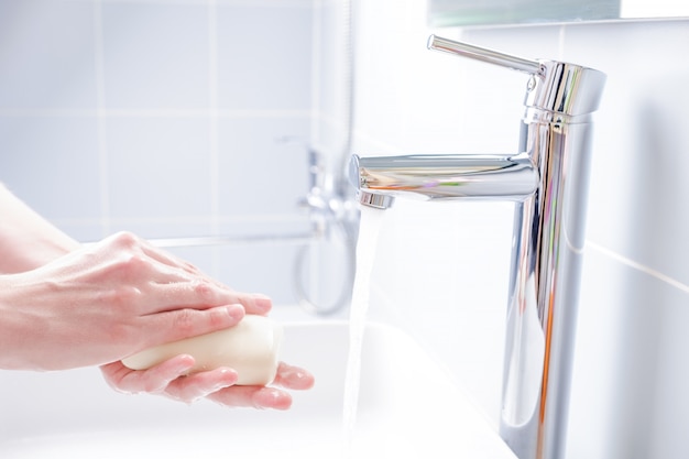 Homem lavando as mãos com sabão no banheiro