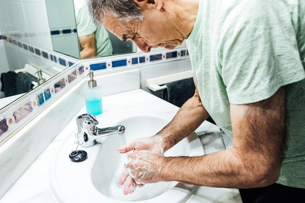 Homem lavando as mãos no banheiro com sabonete para não se infectar com o coronavírus. conceito covid.