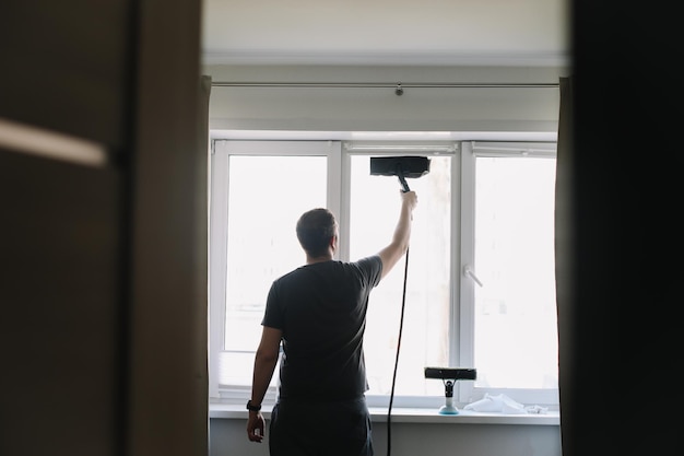 Homem lavando e limpando a janela em casa Trabalho doméstico e higiene doméstica