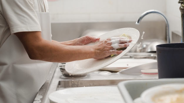 Homem lavando louça na pia de restaurante