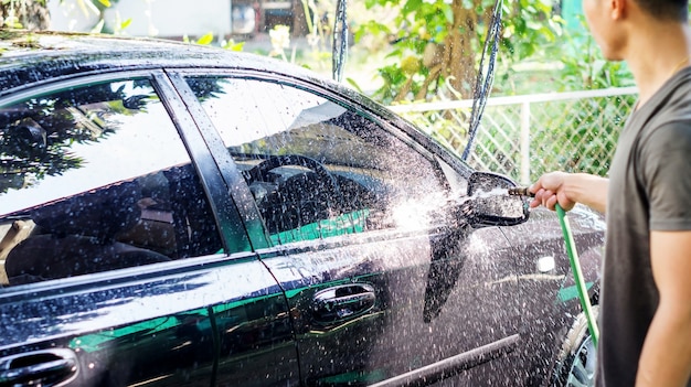 Homem lavando o carro preto.