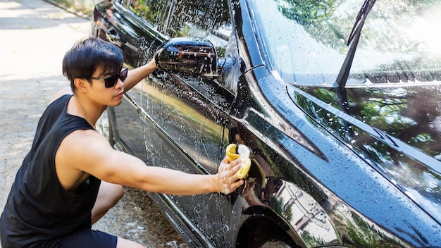 Homem lavando um carro preto.