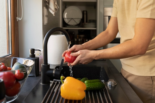 Homem lavando vegetais na pia da cozinha